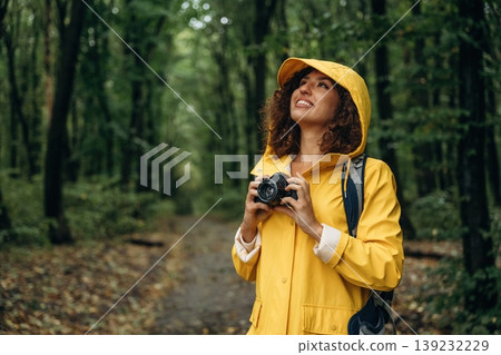 Ready to make a photos. Young woman enjoying nature in the forest under the rain Ready to make a photos. Young woman enjoying nature in the forest under the rain 139232229