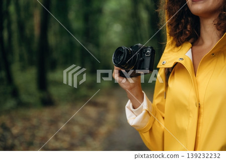 Camera in hand. Woman is in the forest during rain, enjoying the nature Camera in hand. Woman is in the forest during rain, enjoying the nature 139232232