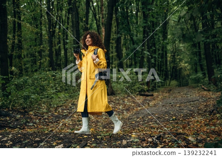Professional photographer is with camera. Young woman enjoying nature in the forest under the rain 139232241
