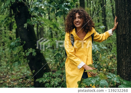 Hiking conception, with backpack. Young woman enjoying nature in the forest under the rain Hiking conception, with backpack. Young woman enjoying nature in the forest under the rain 139232268