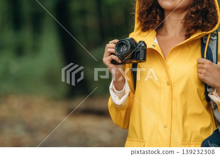 Camera in hand. Woman is in the forest during rain, enjoying the nature Camera in hand. Woman is in the forest during rain, enjoying the nature 139232308