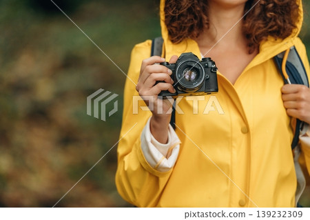 Camera in hand. Woman is in the forest during rain, enjoying the nature Camera in hand. Woman is in the forest during rain, enjoying the nature 139232309