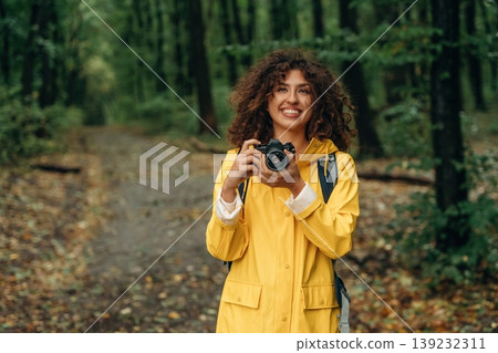 Photographer is with camera. Young woman enjoying nature in the forest under the rain 139232311