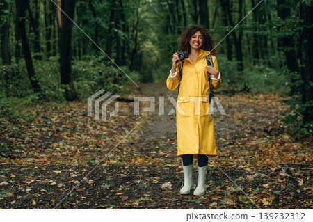 Photographer is with camera. Young woman enjoying nature in the forest under the rain Photographer is with camera. Young woman enjoying nature in the forest under the rain 139232312