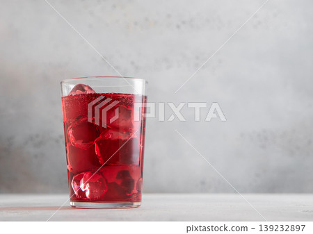 Glass of cold cider with dark berries with ice cubes on light table background. Glass of cold cider with dark berries with ice cubes on light table background. 139232897