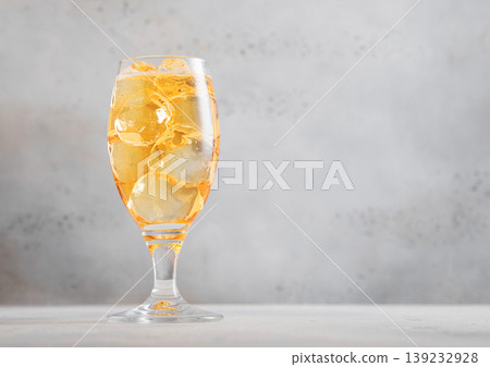 Glass of cold natural apple cider with ice cubes on light table background. 139232928