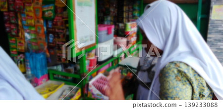 Schoolgirls shopping in a small shop with a blurry background. Schoolgirls shopping in a small shop with a blurry background. 139233088