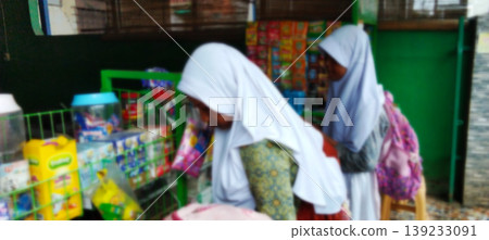 Schoolgirls shopping in a small shop with a blurry background. Schoolgirls shopping in a small shop with a blurry background. 139233091