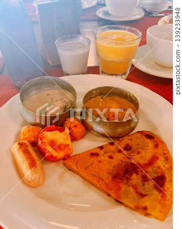 Enjoy breakfast at a resort in Kerala, South India. A Western-Indian fusion plate featuring authentic Indian curry, paratha, and sausage. Enjoy breakfast at a resort in Kerala, South India. A Western-Indian fusion plate featuring authentic Indian curry, paratha, and sausage. 139233948