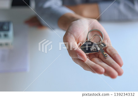 Hand giving house key. Concept for buying, selling, renting or leasing a new home. 139234332