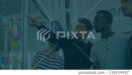 Pointing man in navy sweater highlighting color wheel on glass whiteboard in office, sticky notes Pointing man in navy sweater highlighting color wheel on glass whiteboard in office, sticky notes 139234497