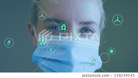 Mid-adult researcher wearing surgical mask analyzing floating energy and eco icons in clinic Mid-adult researcher wearing surgical mask analyzing floating energy and eco icons in clinic 139234545