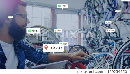 Leaning bicycle technician checking red bicycle gears at bike shop, with tablet overlay, copy space Leaning bicycle technician checking red bicycle gears at bike shop, with tablet overlay, copy space 139234550