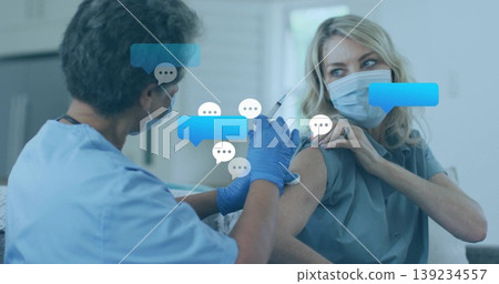 Nurse in blue scrubs injecting vaccine with syringe into arm in clinic, with chat bubble graphics Nurse in blue scrubs injecting vaccine with syringe into arm in clinic, with chat bubble graphics 139234557
