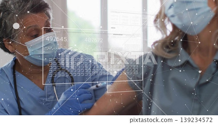 Administering masked nurse in blue scrubs giving vaccine at clinic, with syringe and data overlays Administering masked nurse in blue scrubs giving vaccine at clinic, with syringe and data overlays 139234572