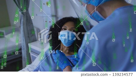 Clinician in scrubs and face shield pressing stethoscope on masked patient in hospital bed 139234577