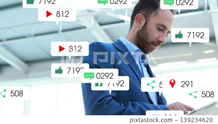 Business professional man holding tablet computer and viewing floating media icons in office lobby Business professional man holding tablet computer and viewing floating media icons in office lobby 139234620