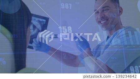 Male dentist wearing gloves holding dental imaging strip in operatory, with x-ray monitor and bib Male dentist wearing gloves holding dental imaging strip in operatory, with x-ray monitor and bib 139234642
