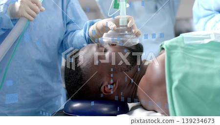 Holding anesthesia mask, staff in scrubs securing patient airway in operating room, with drape Holding anesthesia mask, staff in scrubs securing patient airway in operating room, with drape 139234673