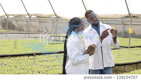 Watching two researchers in lab coats analyzing seedling in greenhouse with tablet and insect traps Watching two researchers in lab coats analyzing seedling in greenhouse with tablet and insect traps 139234707