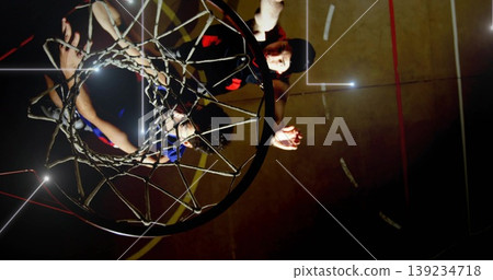 Jumping adult opponents reaching beneath court hoop and net, wearing red knit cap and blue jersey Jumping adult opponents reaching beneath court hoop and net, wearing red knit cap and blue jersey 139234718