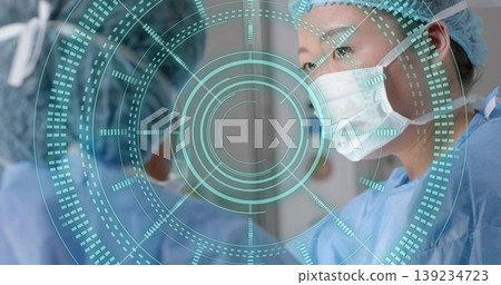 Korean female surgeon scanning AR interface in hospital OR, in blue scrubs, caps and masks Korean female surgeon scanning AR interface in hospital OR, in blue scrubs, caps and masks 139234723