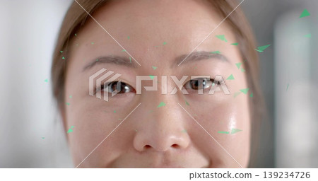 Showing close-up Korean woman scanning face in softly lit interior, with green triangular fragments Showing close-up Korean woman scanning face in softly lit interior, with green triangular fragments 139234726