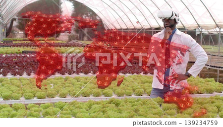 Surveying hydroponic lettuce trays in greenhouse arches, VR headset showing world map, copy space Surveying hydroponic lettuce trays in greenhouse arches, VR headset showing world map, copy space 139234759
