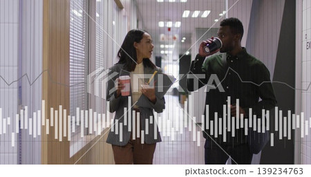 Walking colleagues discussing work under recessed lights in hallway, with coffee cups, clipboard Walking colleagues discussing work under recessed lights in hallway, with coffee cups, clipboard 139234763