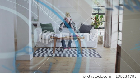 Studying man wearing flannel shirt and headphones in living room, with notebooks and loose papers Studying man wearing flannel shirt and headphones in living room, with notebooks and loose papers 139234793