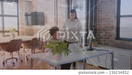 Two coworkers wearing business attire reviewing laptop content in open office with potted plant Two coworkers wearing business attire reviewing laptop content in open office with potted plant 139234852