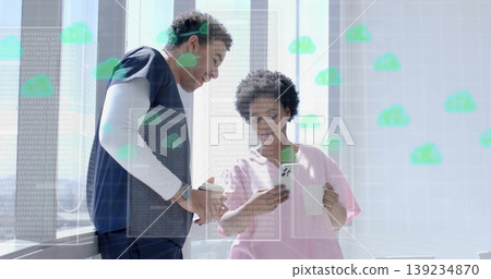 Standing pair wearing scrubs checking wristwatch and smartphone in lounge, digital overlay Standing pair wearing scrubs checking wristwatch and smartphone in lounge, digital overlay 139234870