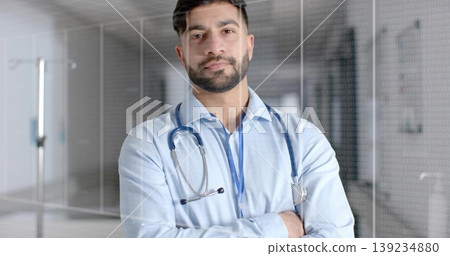 Indian doctor standing with crossed arms in hospital corridor, with stethoscope and ID badge Indian doctor standing with crossed arms in hospital corridor, with stethoscope and ID badge 139234880