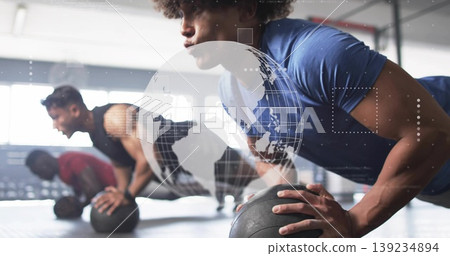 Performing push-up man wearing blue shirt on black medicine ball on rubber gym floor, copy space Performing push-up man wearing blue shirt on black medicine ball on rubber gym floor, copy space 139234894