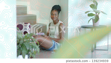 Woman wearing vest writing in notebook at home near stairs, with pen tote bag and plant Woman wearing vest writing in notebook at home near stairs, with pen tote bag and plant 139234939