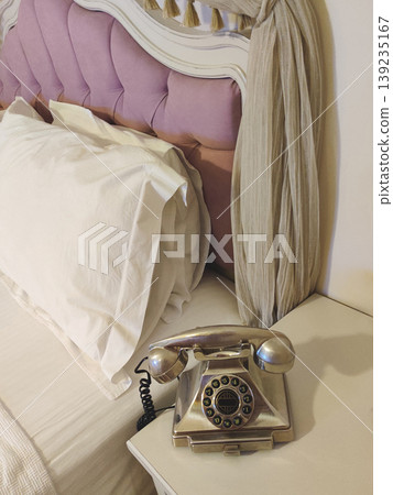 Vintage rotary-style telephone on a bedside table Vintage rotary-style telephone on a bedside table 139235167