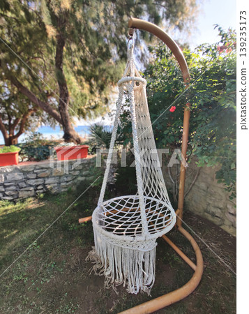 White macrame hanging chair in a sunny garden in Turkey White macrame hanging chair in a sunny garden in Turkey 139235173