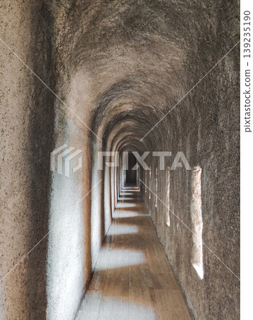 Long narrow stone corridor with arched ceiling and small windows in Turkey 139235190