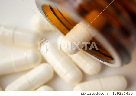 medicine pills capsule spilling out of bottle on white background 139235436