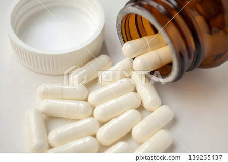 medicine pills capsule spilling out of bottle on white background medicine pills capsule spilling out of bottle on white background 139235437