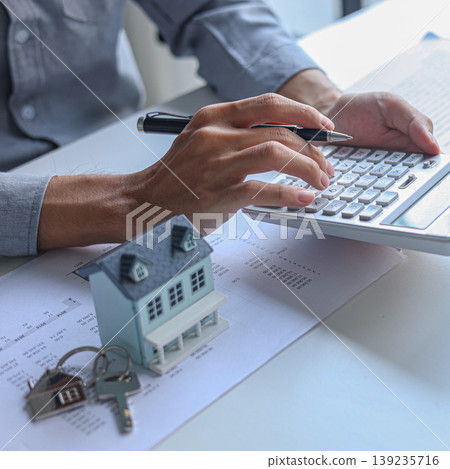 A person using calculator to determine costs of housing, such as mortgage payment, down payment or closing fees associated with property purchase. 139235716