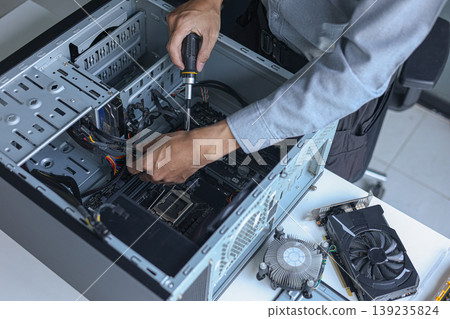 Computer engineer assembling high-performance PC at workshop desk. Computer engineer assembling high-performance PC at workshop desk. 139235824