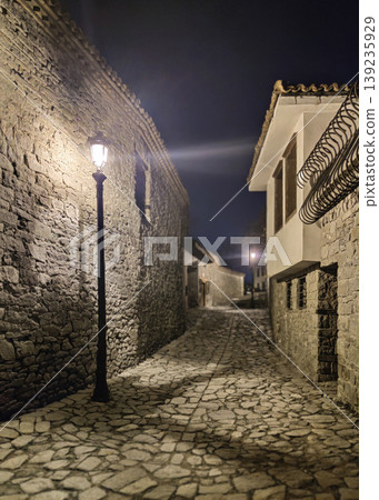 Night view of a narrow cobblestone street with stone walls and vintage lamp Night view of a narrow cobblestone street with stone walls and vintage lamp 139235929