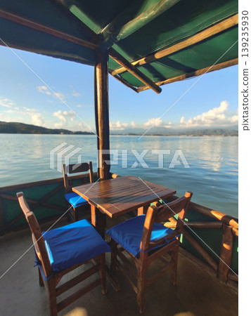 Wooden table and chairs on a boat terrace with sea view Wooden table and chairs on a boat terrace with sea view 139235930