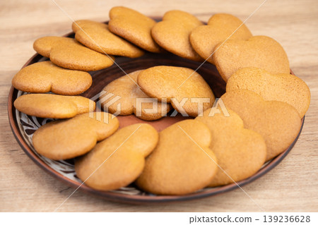 Plate of heart-shaped ginger cookies on a wooden background 139236628