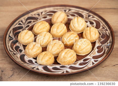 Traditional walnut-shaped cookies on a patterned ceramic plate 139236630