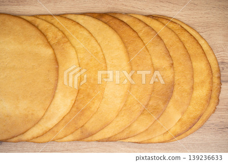 Thin golden honey cake layers stacked on a wooden surface Thin golden honey cake layers stacked on a wooden surface 139236633