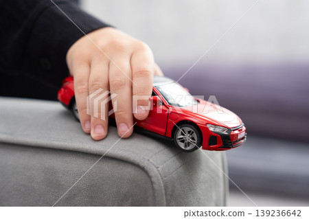 Child's hand playing with a red toy sports car Child's hand playing with a red toy sports car 139236642