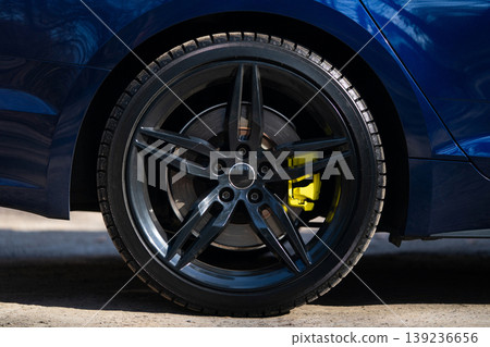 Close-up of a black multi-spoke wheel with a yellow brake caliper 139236656
