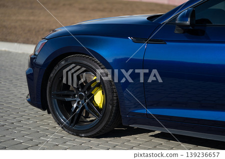 Side view of the front wheel and fender of a dark blue luxury sedan Side view of the front wheel and fender of a dark blue luxury sedan 139236657